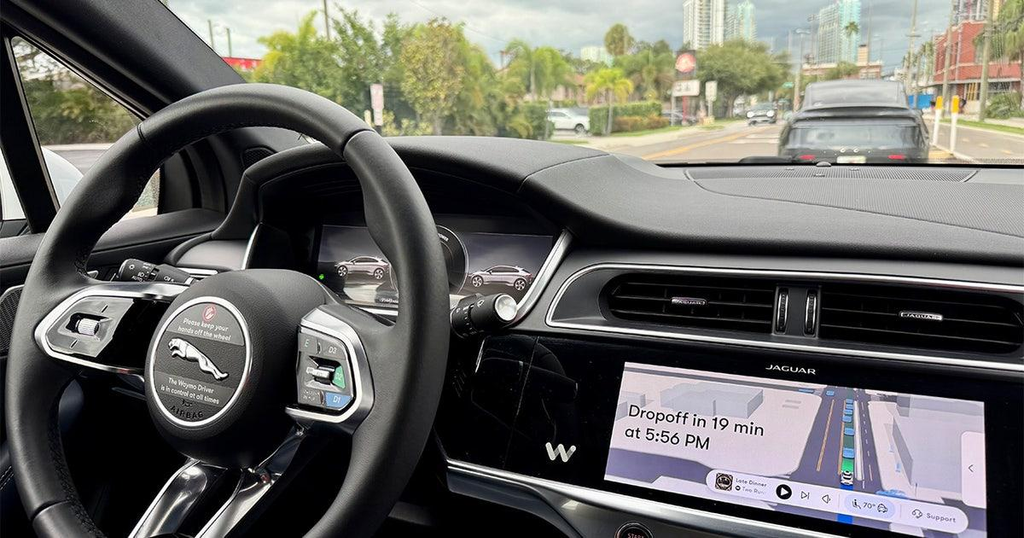 The interior and steering wheel of a Waymo Ipace vehcle